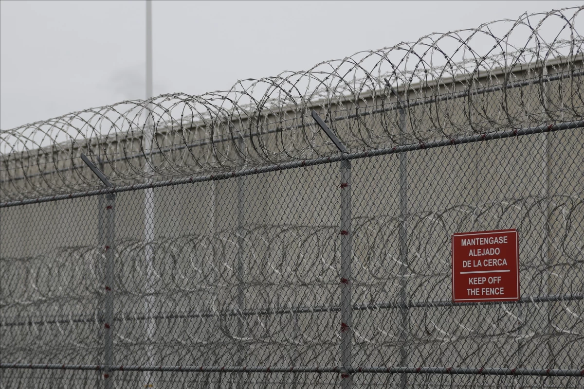Barbed wire fencing is shown behind a sign in English and Spanish in a recreation yard used by detainees during a media tour of the U.S. Immigration and Customs Enforcement detention center in 2019 in Tacoma, Wash.