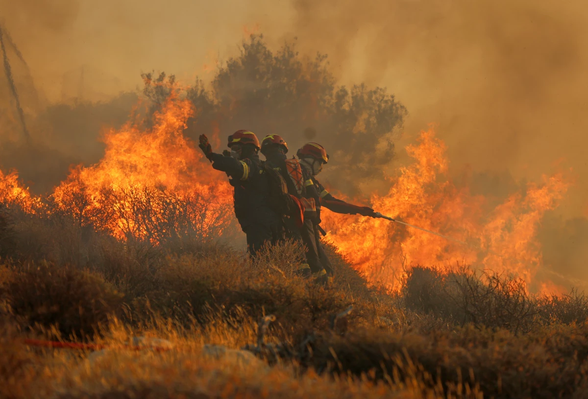 Firefighter uses a hose as the try to extinguish the blaze near the town of Ierapetra on the south coast of Crete island, Greece on Thursday as a fast-moving wildfire prompted authorities to clear villages and coastal areas, officials said.