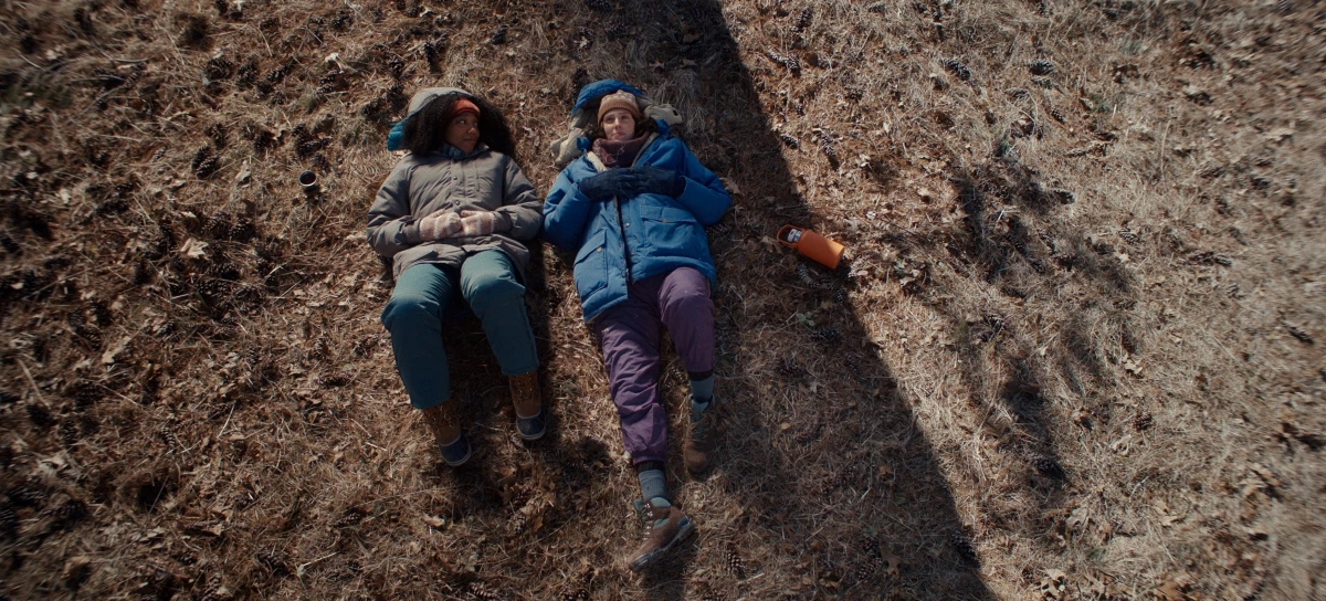 Lydie, played by Naomi Ackie (left), lays on the ground next to Agnes (Eva Victor) in this still from Sorry, Baby.