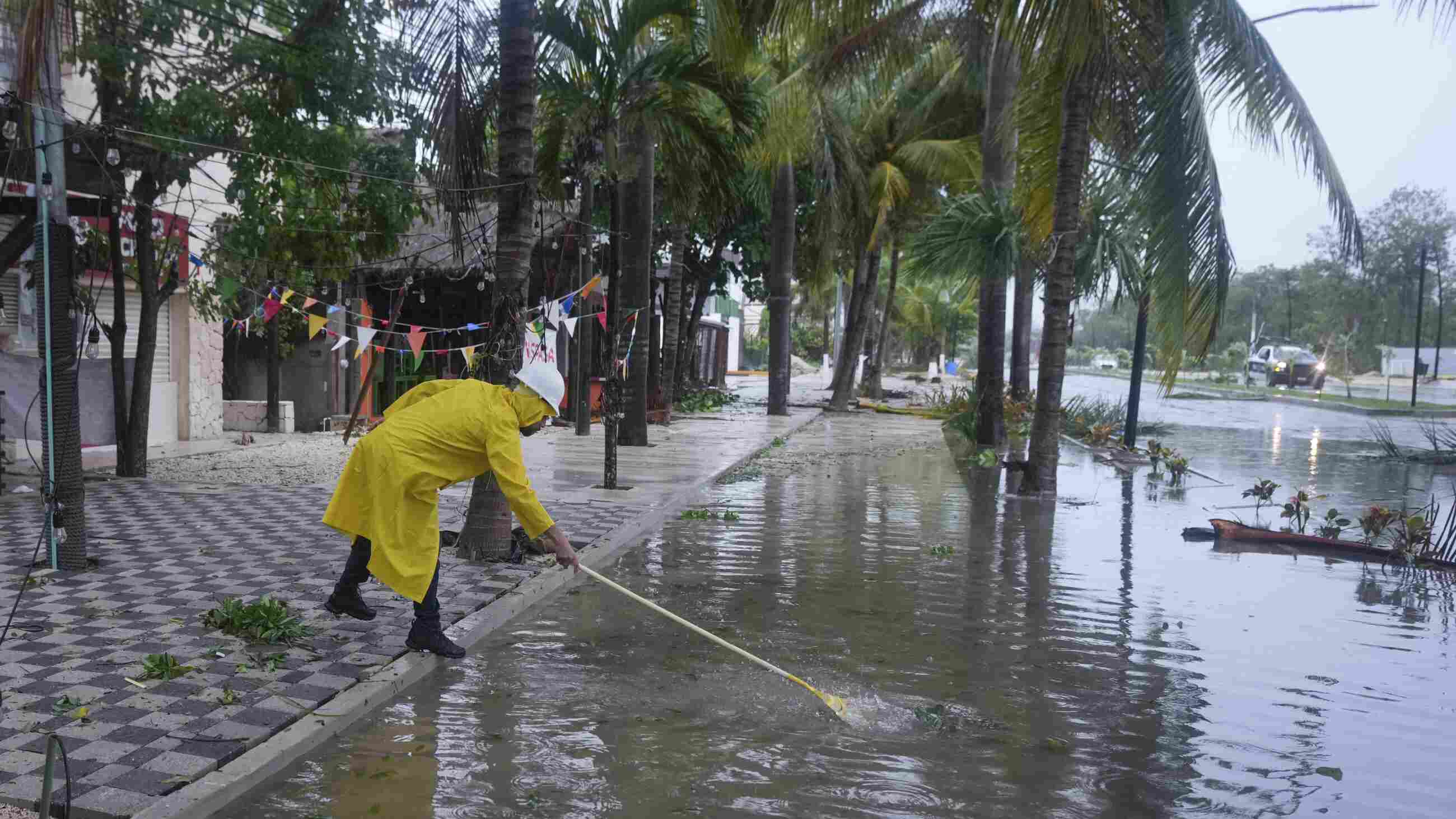 A man unclogs a drain in the aftermath of Hurricane Beryl, in Tulum, Mexico, on Friday.