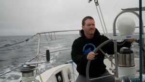 Sailor Matt Rutherford at the helm of a sailboat. He hopes to be the first to circumnavigate the Arctic Circle alone.