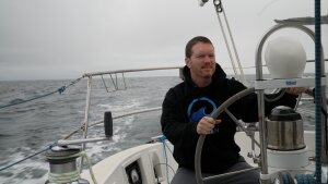 Sailor Matt Rutherford at the helm of a sailboat. He hopes to be the first to circumnavigate the Arctic Circle alone.