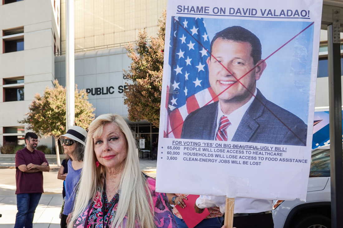 Stacey Augustson holds up a homemade sign during the protest outside U.S. Rep. David Valadao’s district office in Bakersfield.