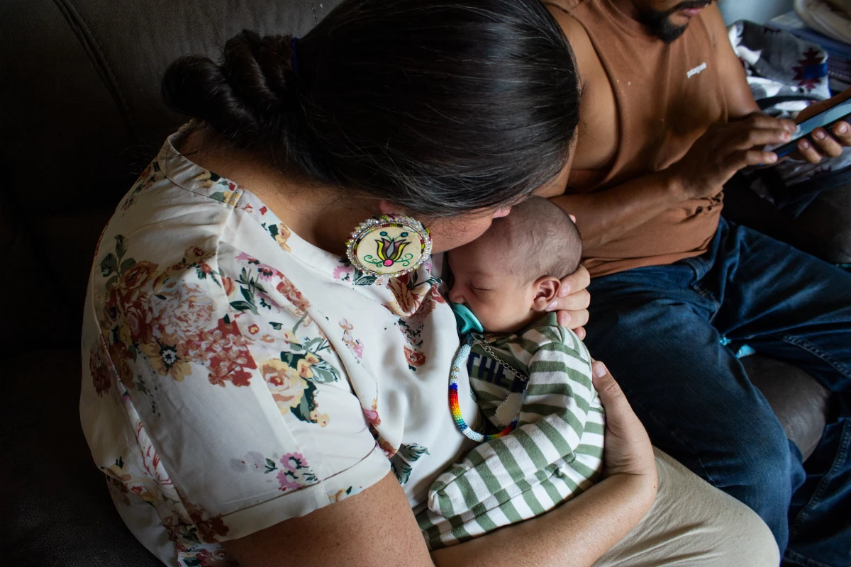 At her first check in since his birth, Doula Misty Pipe kisses the top of Grover's head as his father, Torey WolfVoice, scrolls through photos of the baby boy's namesake grandfather.