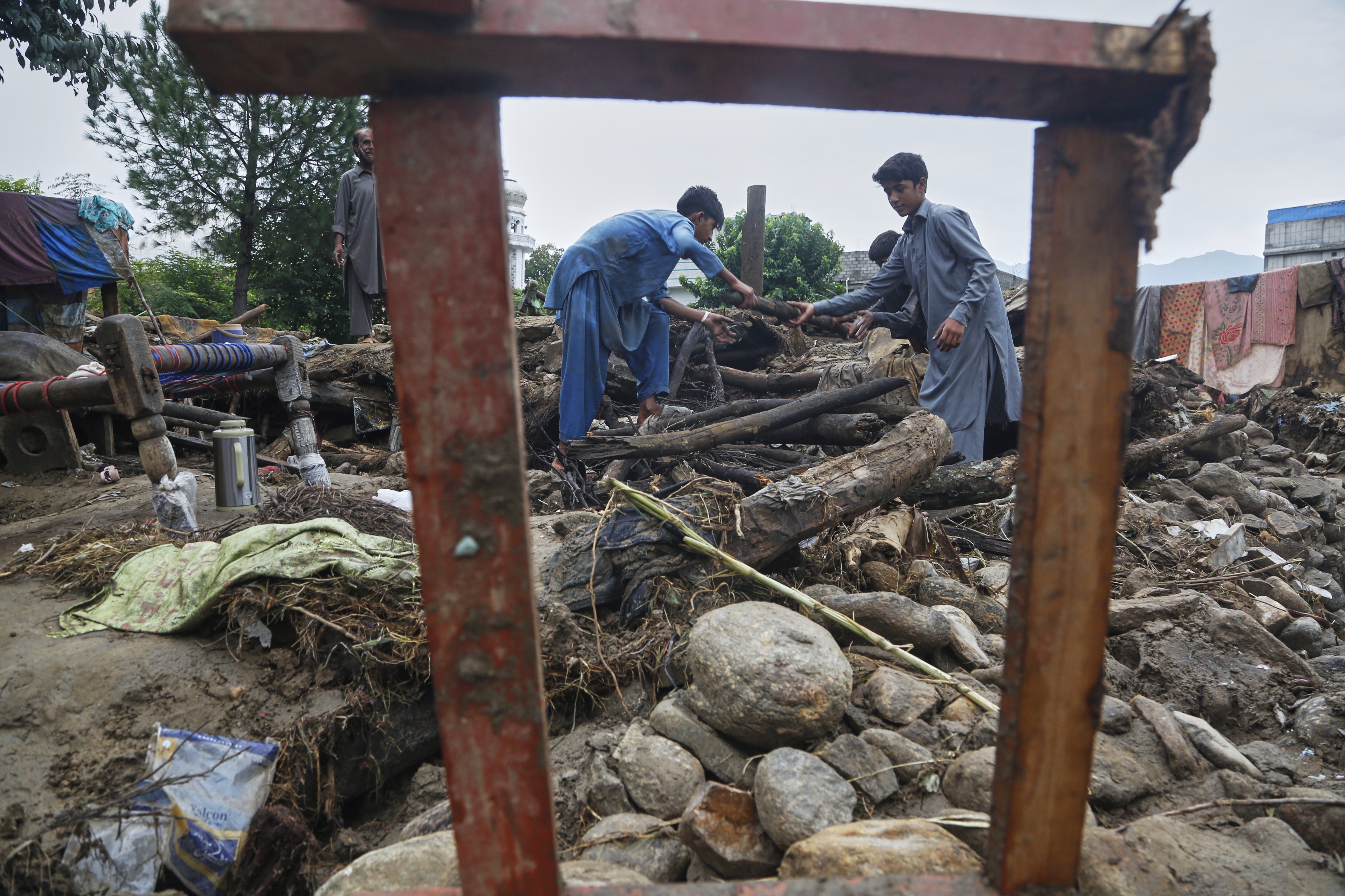 Boys collect wood and other useful items through the rubble of their damaged home following Friday