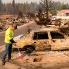 A utility worker marks a spot where a suspected gas line is at a burned property during the Old Trails fire in Spokane, Washington, on Aug. 4.