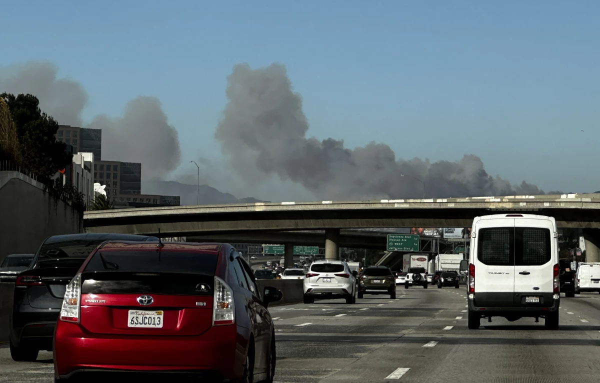 Smoke from a brush fire in the Pacific Palisades rises over the 405 freeway in Los Angeles on Tuesday.