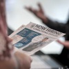 A person holds a "now hiring" flyer.