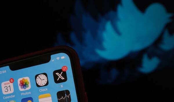 The X logo is displayed on the app on a smartphone screen.