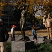 Pedestrians look at a statue of Donald Trump behind Gerhard Marcks' sculpture Maja, in Maja Park in Philadelphia.