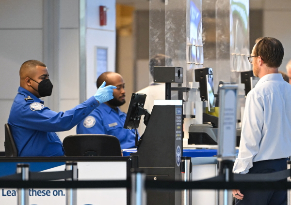 TSA agents check passenger identity documents at a security checkpoint at Reagan National Airport on the first day of the government shutdown in Arlington, Va., on Oct. 1. Some airports are declining to play a video where Homeland Security Secretary Kristi Noem blames Democrats for the government shutdown.