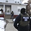 ICE agents approach a house before detaining two people on January 13, 2026 in Minneapolis, Minnesota.