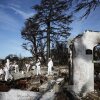 Volunteers dressed in white hazmat suits help a homeowner search for personal items in the remains of a home that burned in the Palisades Fire in January. The remains include a brick chimney and exterior doorway that stand alone amid debris on the ground.