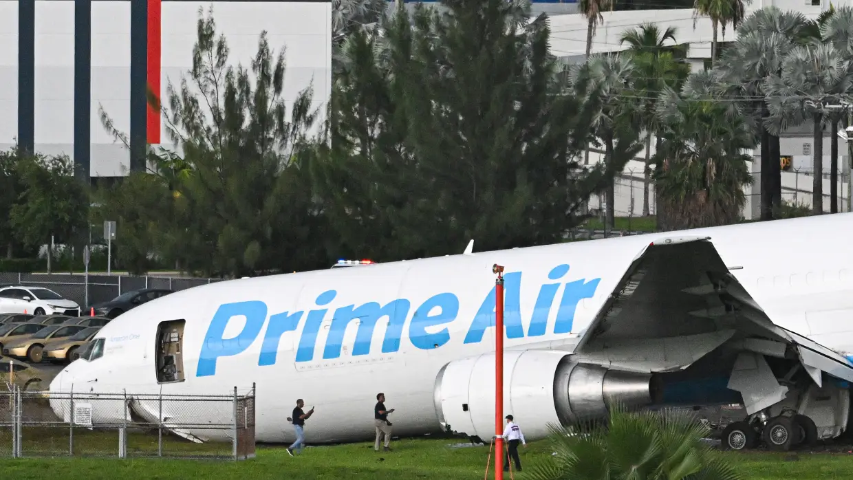 Officials investigate a Prime Air cargo plane at Miami International Airport after it overran the runway at Miami International Airport in Miami, Fla., on Sept. 6, 2026. An Amazon cargo plane overshot a runway as it landed in Miami, crashing into vehicles and catching fire, officials said.