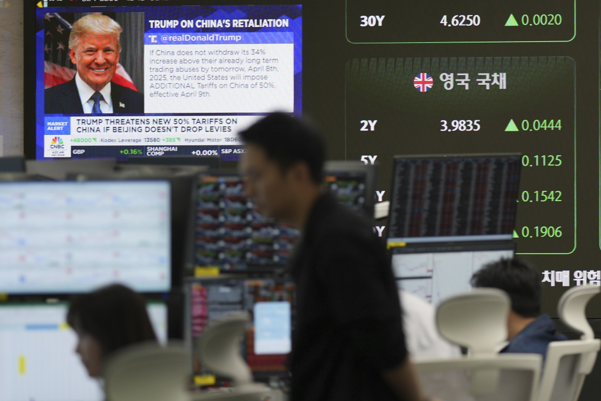 Currency traders watch computer monitors near the screen showing news reporting with a picture of President Donald Trump at a foreign exchange dealing room in Seoul, South Korea on Tuesday.