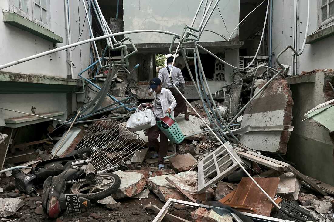 A resident carries belongings over debris