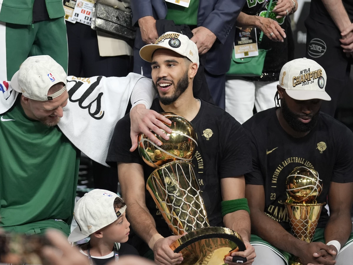 Boston Celtics forward Jayson Tatum, center, holds the Larry O'Brien Championship Trophy as he celebrates with center Kristaps Porzingis, left, and guard Jaylen Brown, right, after the Celtics won the NBA championship with a Game 5 victory over the Dallas Mavericks on Monday in Boston.