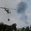 A Florida Forest Service firefighter's helicopter prepares to dump a bucket load of water on a wildfire on April 14, 2026, in Naples, Florida. Conditions in the area are conducive to wildfires due to the lack of rain, causing drought conditions.