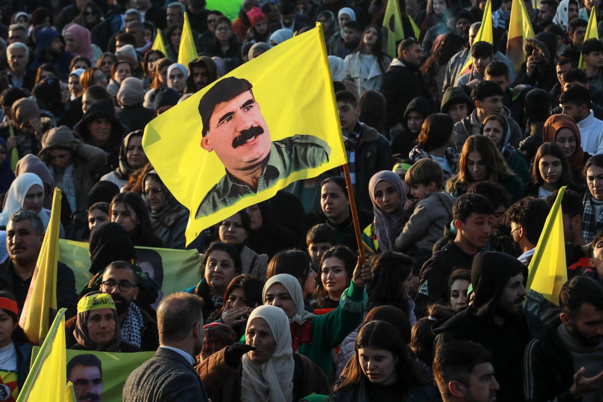 A woman waves a flag bearing a picture of the founder of the Kurdistan Workers' Party (PKK) Abdullah Ocalan, as people gather in the Kurdish-majority city of Qamishli in northeastern Syria to listen to a message from the jailed leader on Feb. 27. Ocalan called for his Kurdish militant force to disband and his fighters to lay down their arms.