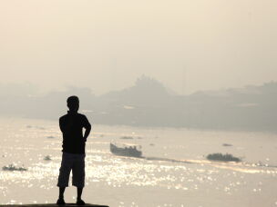 A man is silhouetted against the haze from wildfires that blankets Musi River in Palembang, South Sumatra, Indonesia, Sunday, Aug. 23, 2026.