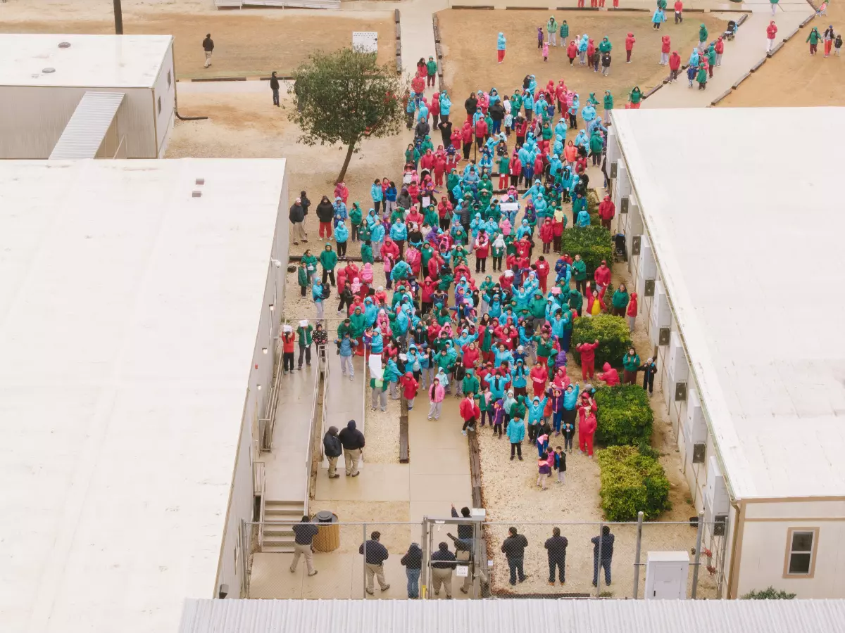 Detainees held at the South Texas Family Residential Center wave signs during a demonstration in Dilley, Texas, Saturday, Jan. 24, 2026.