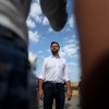 This photo shows Sen. JD Vance of Ohio, the Republican vice presidential nominee, speaking to reporters in front of the border wall with Mexico on Sept. 6 in San Diego. Wearing jeans and a white shirt, he's standing against a blue sky with white clouds.