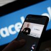 In this illustration photo taken in Los Angeles on October 28, 2021, a person watches on a smartphone as Facebook CEO Mark Zuckerberg unveils the Meta logo.