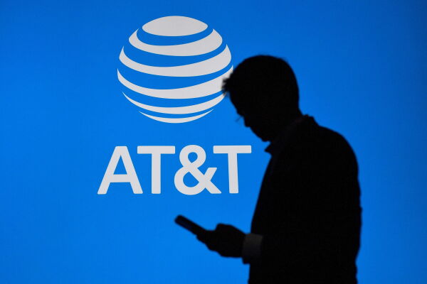 A person walked by an AT&T logo on a blue screen.