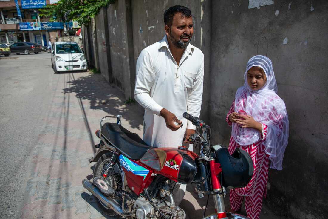 Adil Hussain, 36, and his daughter Ayesha stand outside an HPV vaccination site on Sept. 27, 2025 in Bhara Kahu in Islamabad, Pakistan.