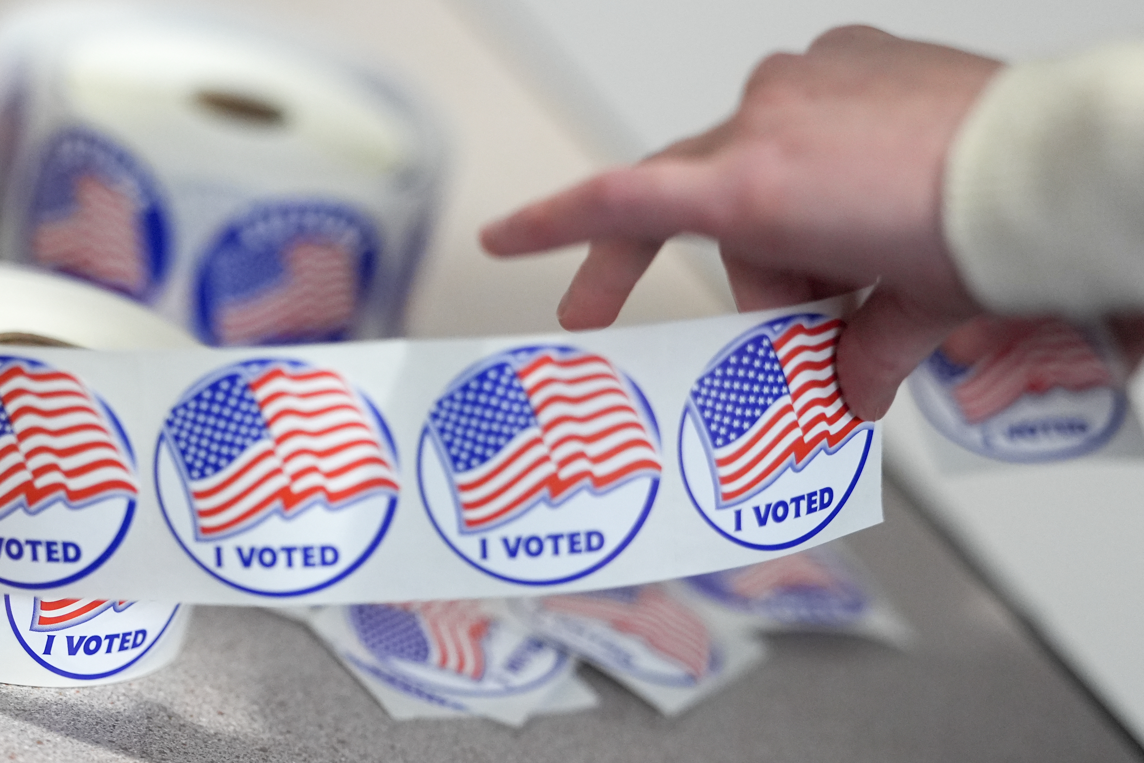 An election worker tears off "I Voted" stickers during the Virginia redistricting referendum at Fairfax Government Center on Tuesday in Fairfax, Va. (AP)