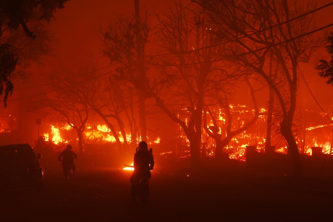 Two persons ride by on motorcycles as the Palisades Fire destroys a neighborhood in the Pacific Palisades neighborhood of Los Angeles.