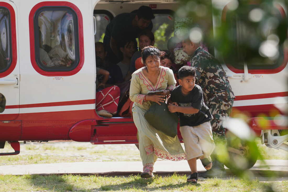 Army soldiers help a family disembark from a helicopter after they are rescued from an area affected by flash flooding in Nepal's Nuwakot district, Friday, Aug. 28, 2026.