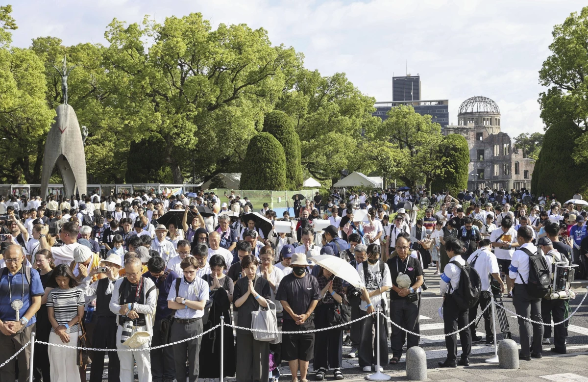 Visitors observe a minute of silence for the victims of the atomic bombing, at 8:15am, the time atomic bomb exploded over the city, at the Hiroshima Peace Memorial Park during the ceremony to mark the 80th anniversary of the bombing in Hiroshima, western Japan, Wednesday, Aug. 6, 2025. (Kyodo News via AP)