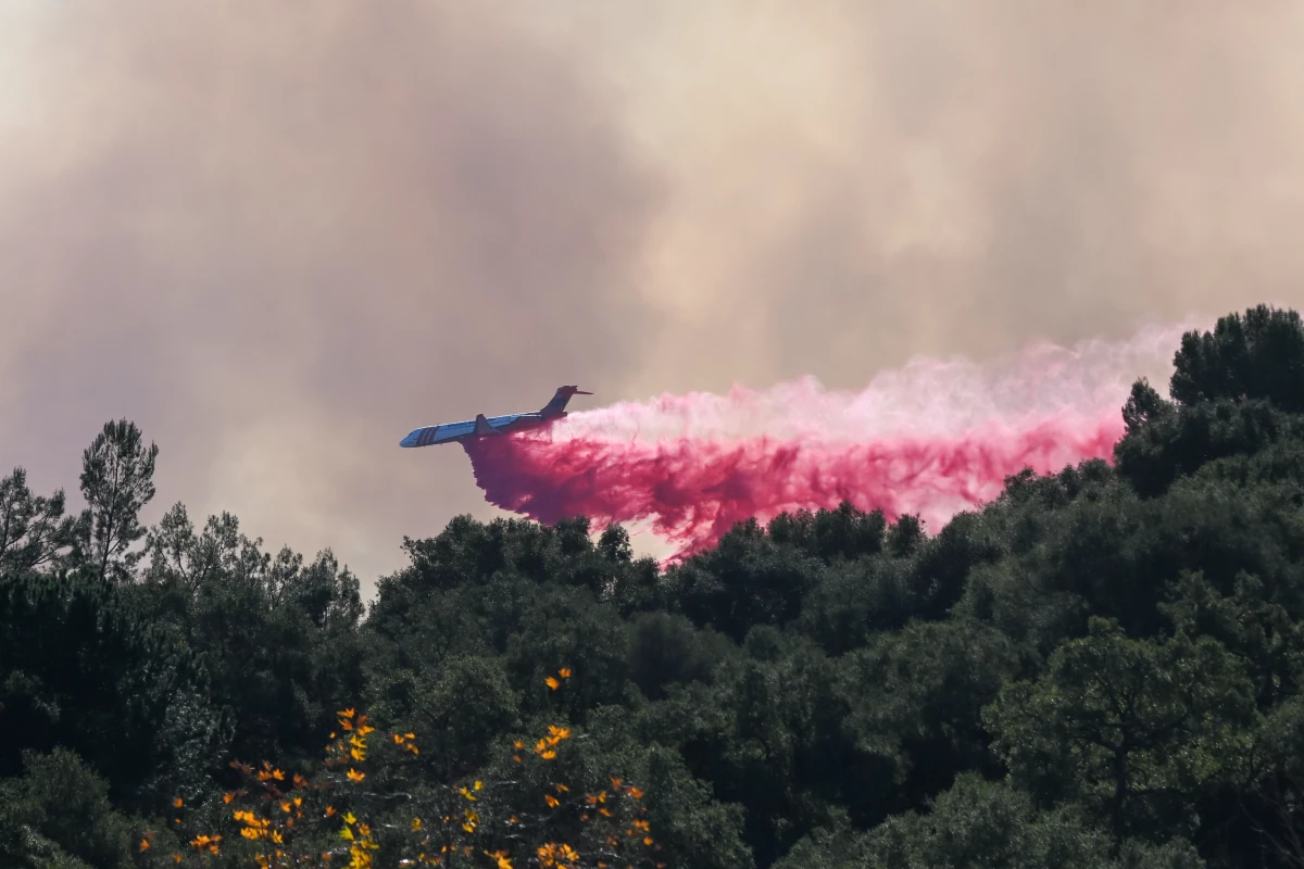 Air tanker planes and helicopters drop water over flames over the Palisades wildfire in Los Angeles on Friday.