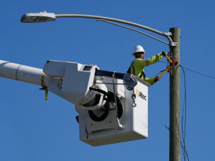 An electrical worker repairs power lines along a street in Gary, Ind, Thursday, Aug. 20, 2026, more than a week after a deadly storm passes through the area.