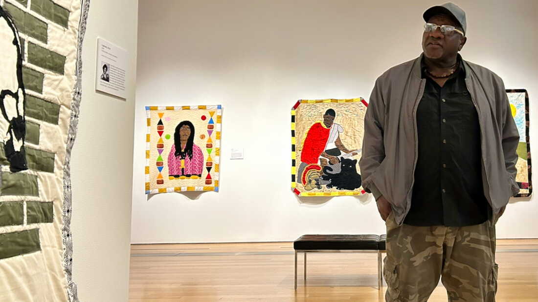 Gary Tyler speaks about his work at the Grand Rapids Art Museum in Michigan. Behind Tyler are his quilts Big Toe, (2024) and Enduring, (2025). They feature two individuals who are incarcerated. He hopes his work draws attention to their plight and humanity.
