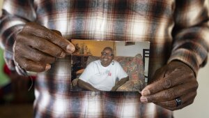 A close-up photo shows Leslie Adams' hands holding a snapshot of his mother. She is smiling broadly.