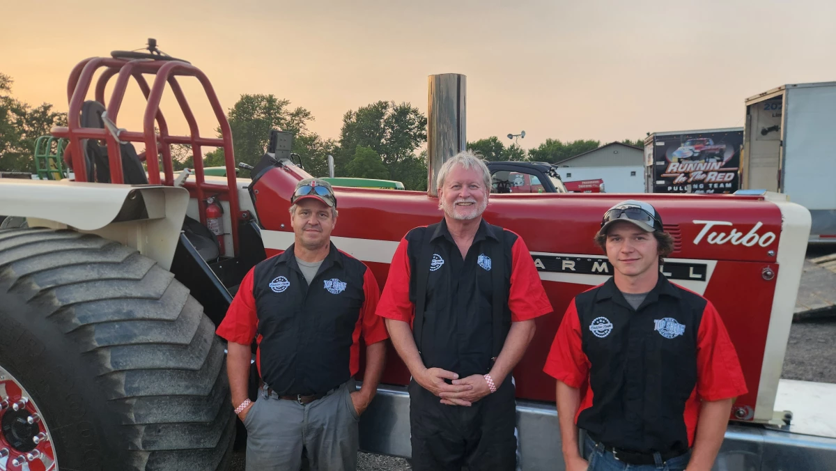 Gary Meals, Bobby Maxwell, and Collin Meals (left to right) prepare to work on the family tractor. Much like in NASCAR or Formula 1, tractor pulling requires teams of support crews to back drivers and keep the gear in tip-top shape.