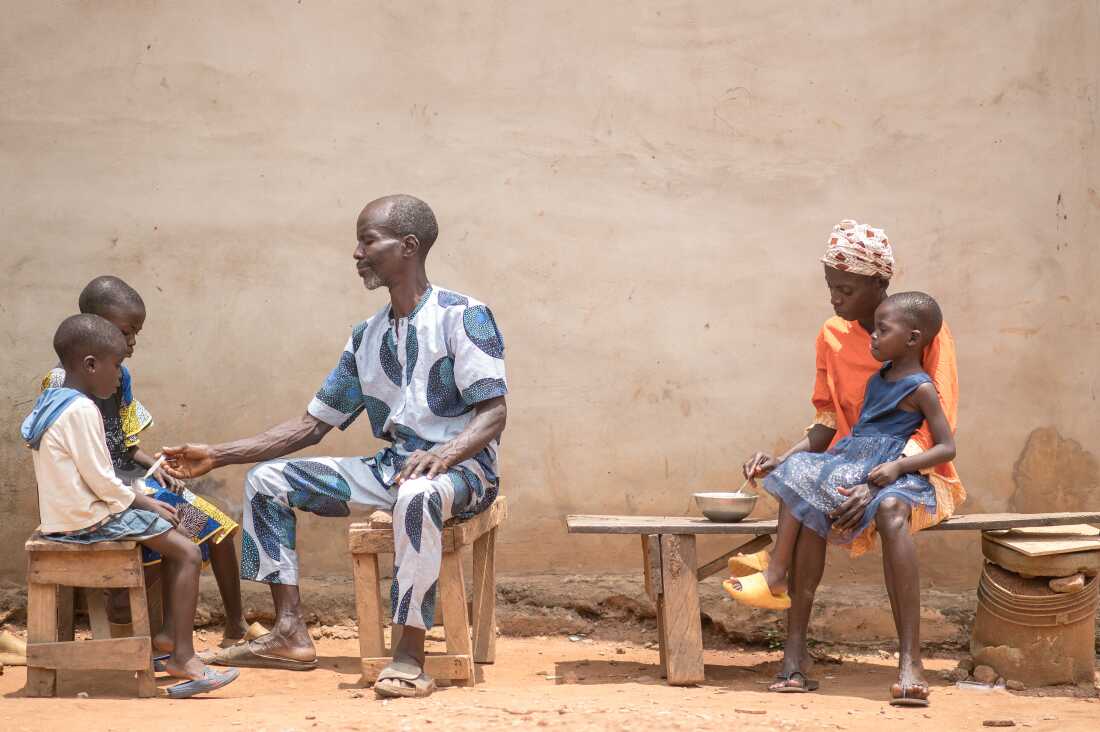 Toyin feeds her 3-year-old daughter, Kudirat, while her husband, Saheed, tends to their other two children.