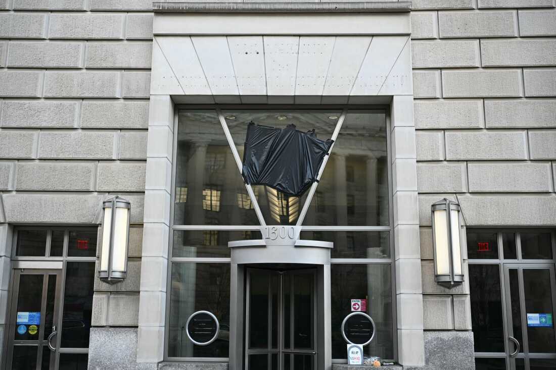 Holes are seen on the building after signage was removed (top) while black plastic covers the logo of the United States Agency for International Development (USAID) at its headquarters in Washington, DC, on February 7, 2025. President Donald Trump on February 7 called for USAID to be shuttered, escalating his unprecedented campaign to dismantle the humanitarian agency.