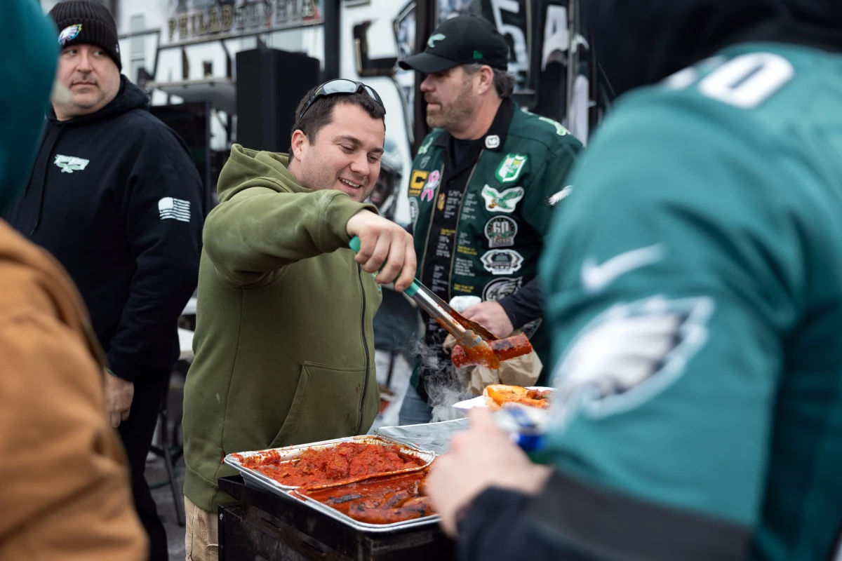Anthony Byrne serves sausage sandwiches at his uncle Ed Callahan's (not pictured) tailgate. The food and drinks are free. In lieu of payment, Callahan asks participants to donate to the raffle which benefits the Eagles Autism Foundation.
