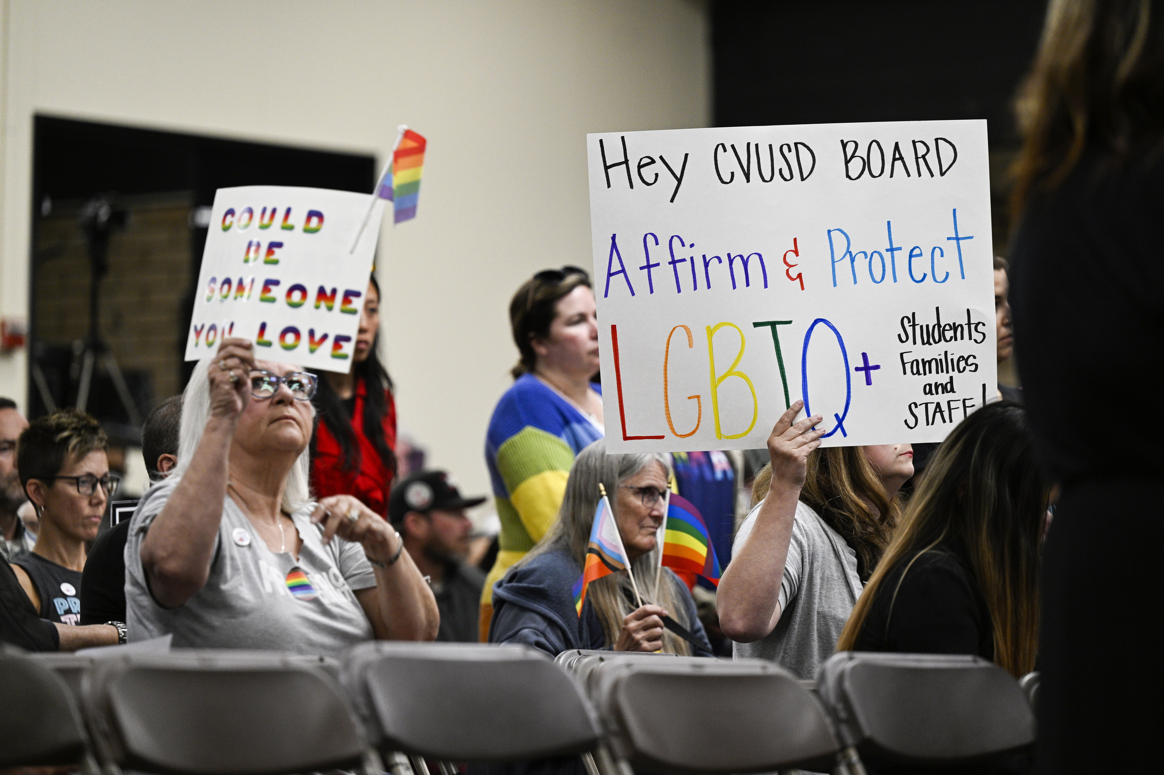 Parents, students, and staff of Chino Valley Unified School District hold up signs in favor of protecting LGBTQ+ policies at Don Antonio Lugo High School, in Chino, Calif., in June 2023. California Gov. Gavin Newsom signed a law Monday barring school districts from passing policies that require schools to notify parents if their child asks to change their gender identification.