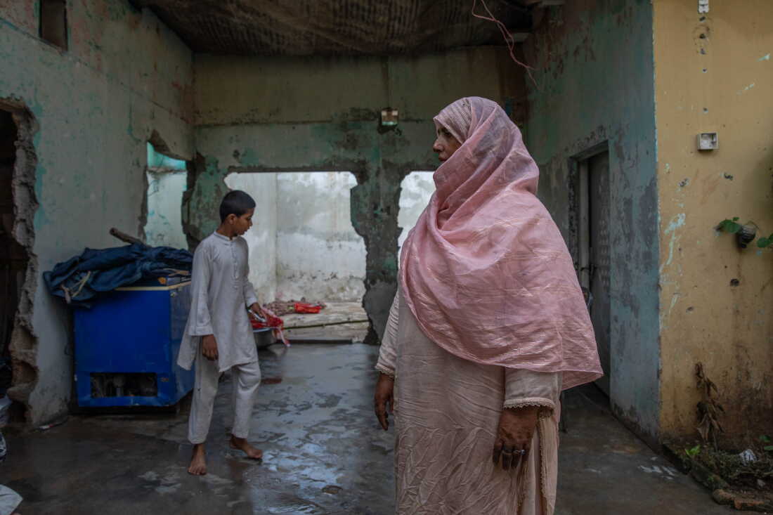 Saida Tanwir stands inside her partially damaged home near Bari Imam on August 20, 2026 in Islamabad, Pakistan. Her son Azeem Ahmed, 16, died while trying to block a bulldozer from crushing their roadside grocery store over the winter.