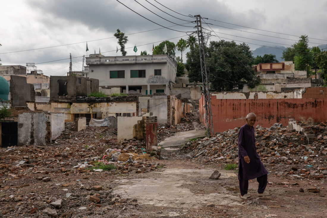 A man walks in front of demolished buildings near Bari Imam on August 20, 2026 in Islamabad, Pakistan.