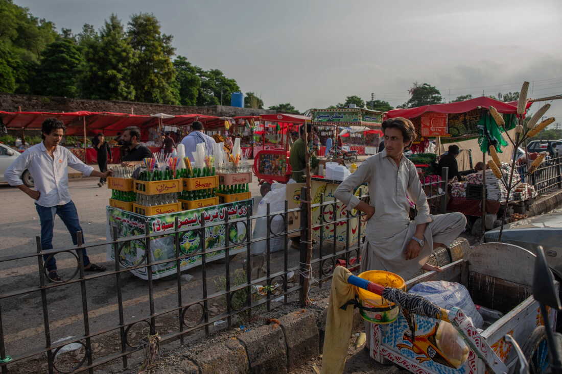 Men sell food and drinks outside Bari Imam on August 20, 2026 in Islamabad, Pakistan. Businesses around the shrine were destroyed along with homes during a demolition drive last winter and spring.