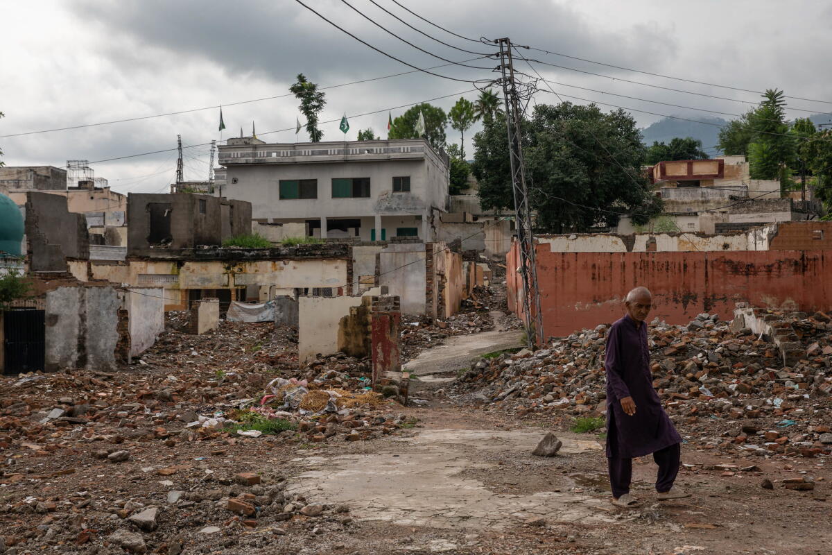 A man walks in front of demolished buildings.