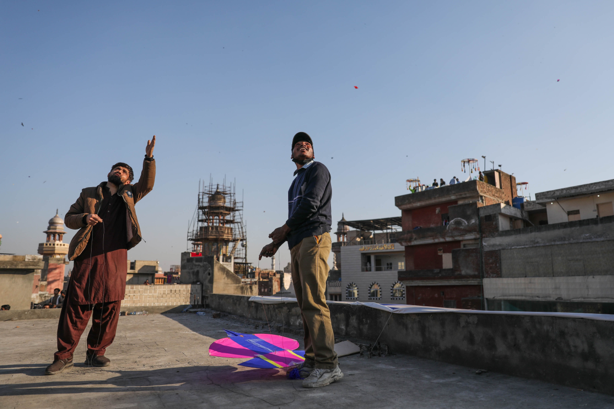 Men gather on a rooftop to fly kites near Delhi Gate in Lahore during Basant.