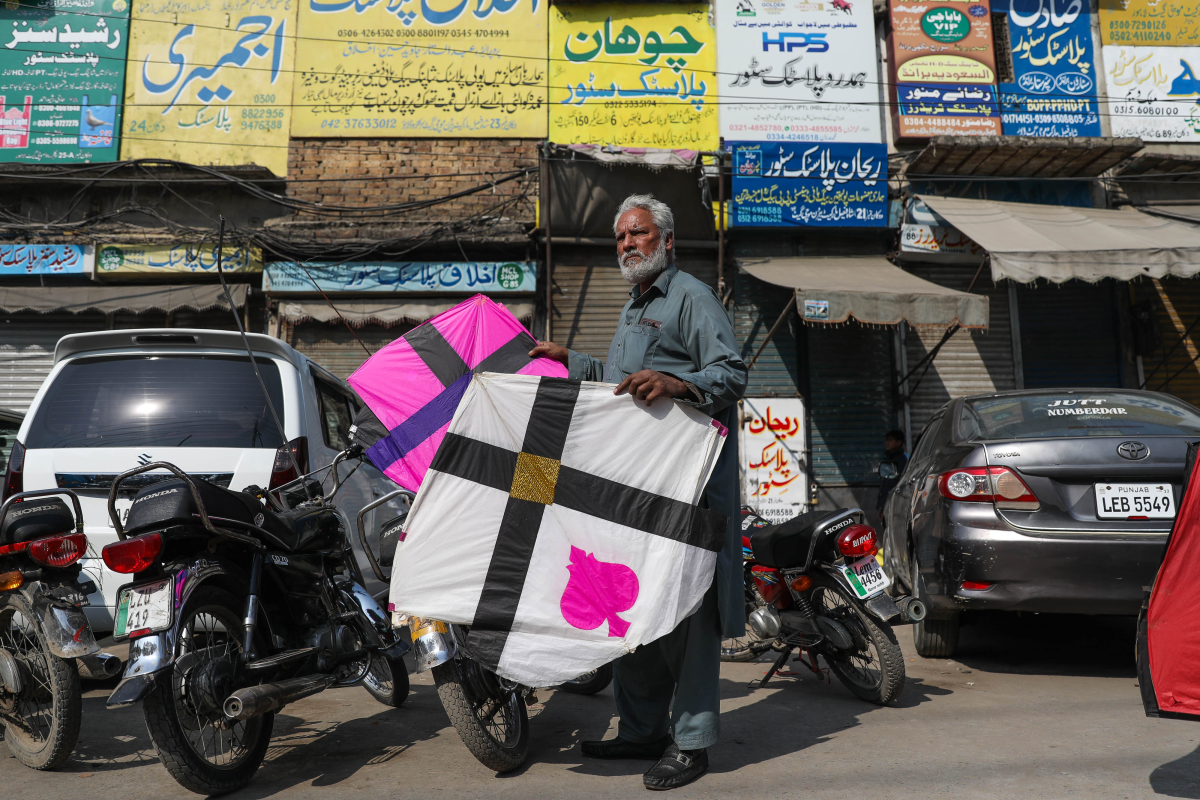 A man holds kites outside a market area near Mochi Gate during Basant.