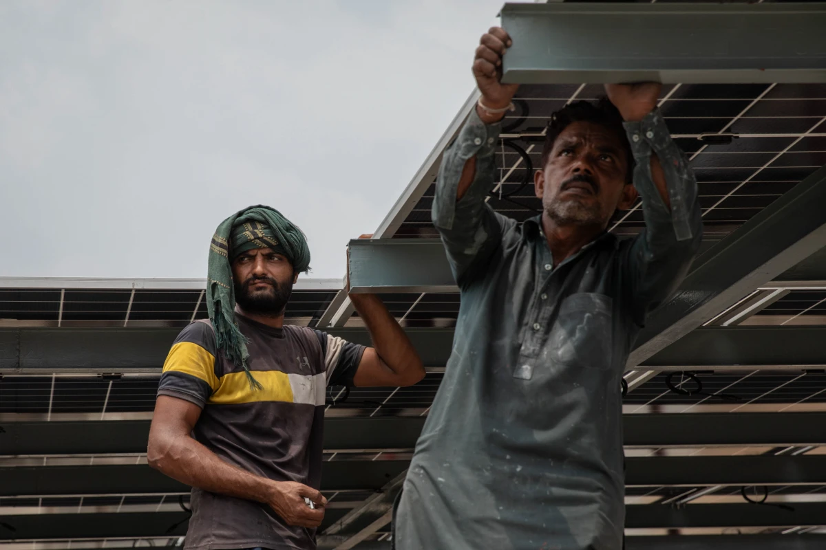 Workers install solar panels on the rooftop of a business on June 30, 2025 in Islamabad, Pakistan.