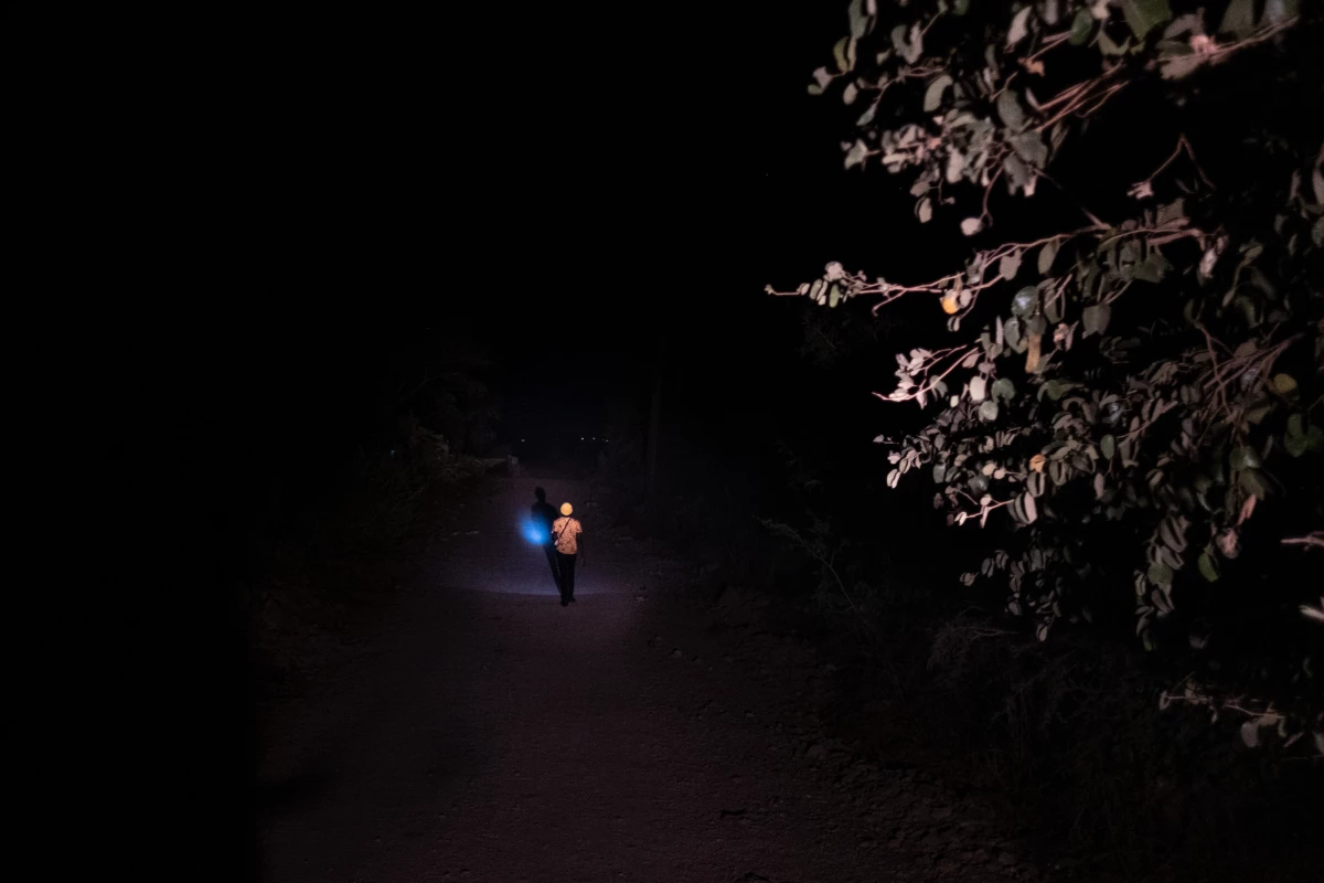 A man uses the light from his mobile phone to navigate an otherwise pitch dark road in an area frequented by elephants in Livingstone, Zambia, where incidents of human-wildlife conflict have been on the rise.